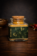 Glass jar with cork lid containing spice mix on a wooden surface