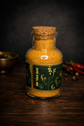 Glass jar with cork lid containing a spice mix on a wooden surface with dark background