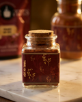 Small glass jar with a cork lid on a marble surface, with a blurred background